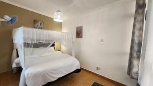 a bedroom with a white bed with a canopy at Kamakis Motel & Lounge in Ruiru