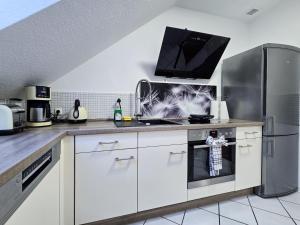 a kitchen with white cabinets and stainless steel appliances at Alpha Apartments in Datteln +12 photos