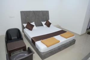 a bedroom with a bed and a chair at Hotel Sky Blue in Surat