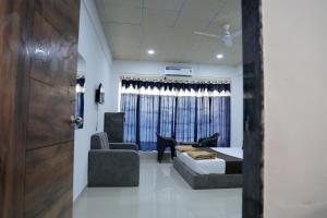 a bedroom with a bed and a couch and a chair at Hotel Sky Blue in Surat