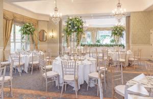 a banquet room with white tables and chairs and chandeliers at Careys Manor Hotel & SenSpa in Brockenhurst +49 photos