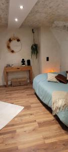 a bedroom with a bed and a wooden floor at A l'ombre des sentiers in Cuisiat