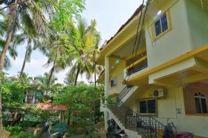 a yellow building with stairs and palm trees at Cardozo beach house in Calangute