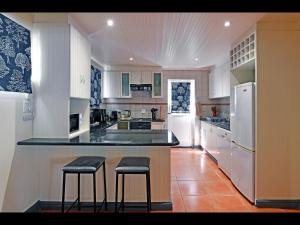 a kitchen with white appliances and two stools at a counter at Sunflower Villa in Franschhoek in Franschhoek
