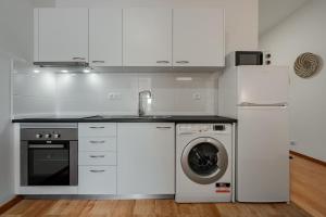 a white kitchen with a washing machine and a sink at Modern studio near Metro in Senhora da Hora