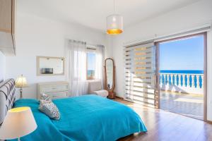 a bedroom with a blue bed with a view of the ocean at Villa Beach Heaven in Pomos +56 photos