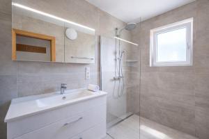 a bathroom with a sink and a glass shower at Seehaus Gori in Maria Wörth +6 photos
