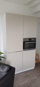 a kitchen with white cabinets and a microwave at Antares-Ameland in Hollum