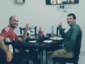 two men sitting at a table with their hands up at Nairobi Transit Lounge in Nairobi