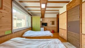 two beds in a small room with a window at Backpacker's Home in Seogwipo