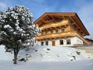a snow covered building with a tree in front of it at Wiererhof in Fügenberg
