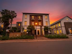 a large white building with a sunset in the background at Tayfin Royale Hotel & Conference Centre in Centurion