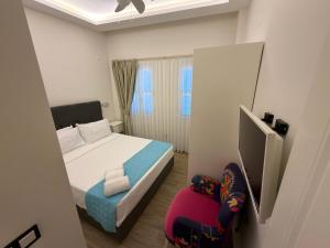 a small bedroom with a bed and a chair at Çeşme Kale Taş Apart in Çeşme