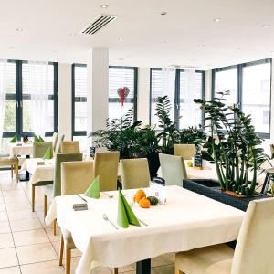 a restaurant with white tables and chairs and plants at Rosi's Dorfwirtschaft in Rottenacker