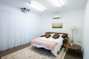 a white bedroom with a bed and a table at Rosewood Terrace in Bathurst