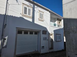 a white building with a garage door next to it at Chez Gilbert-Alojamento Local in Alqueidão da Serra