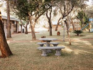 a group of picnic tables in a park with trees at Kudu Kopje Lodge in Kroondal