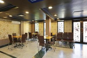 a dining room with tables and chairs and windows at Bengal Inn in Kolkata