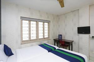 a bedroom with a bed and a desk and a window at Bengal Inn in Kolkata