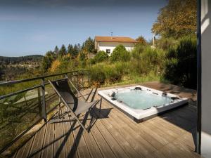 a hot tub sitting on a deck with a chair at Chalet L'Ursus - OVO Network in Gérardmer