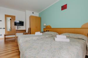 a bedroom with two beds and a flat screen tv at Hotel Spera in Strigno