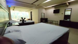 a bedroom with two beds and a television in a room at Hotel Rose Garden in Chittagong