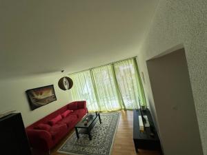 a living room with a red couch and a large window at A room in semi shared flat in Wallisellen
