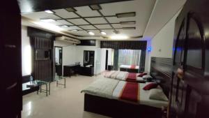 a bedroom with two beds and a desk and a room at Hotel Rose Garden in Chittagong