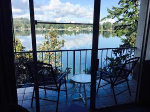 balkon z 2 krzesłami i stołem oraz widokiem na jezioro w obiekcie Flagship Inn w mieście Bremerton