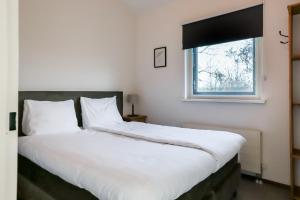 a large white bed in a room with a window at Zilt vakantiehuisje - Rekerlanden 283 in Schoorldam +17 photos