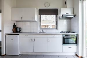 a white kitchen with white cabinets and a window at Zilt vakantiehuisje - Rekerlanden 283 in Schoorldam