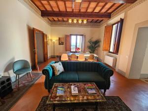 a living room with a green couch and a table at Villa Palazzo Delle Erbe in Casole dʼElsa