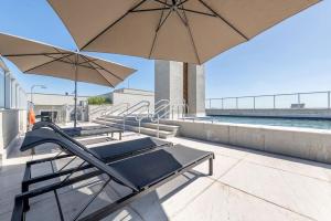 a couple of lounge chairs and umbrellas on a patio at LOFT1304 Maxplaza Canoas in Canoas