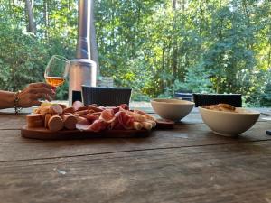 a table with a plate of meat and a glass of wine at Glampingtent Bosgenot in Zedelgem
