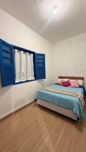 a bedroom with a bed with blue shutters and a window at Casa Colina in Ouro Preto