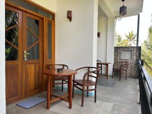 a porch with a table and chairs and a door at Kumarana in Bentota