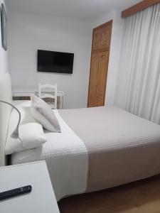 a bedroom with a white bed and a television at El Ancla Ponferrada in Ponferrada