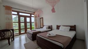 a bedroom with two beds and a large window at New Wasala Guest in Diyatalawa