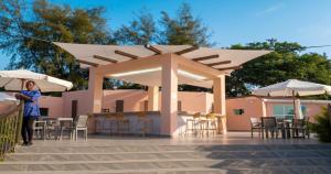 a woman standing in front of a pavilion with tables and chairs at Palma Rima Hotel in Kololi