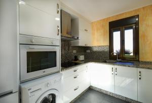 a kitchen with white cabinets and a washer at YourHouse Casa Antonio in Sobrado del Obispo +18 photos