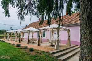 a row of tables and umbrellas in front of a pink building at Kamala Kutir in Somogyvámos
