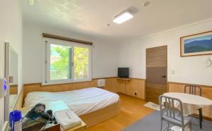 a bedroom with a bed and a table and a window at Backpacker's Home in Seogwipo