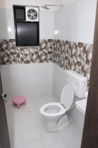 a bathroom with a toilet and a tv on the wall at Manas homes in Gwalior