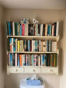 a book shelf filled with books on a wall at Brook Farm Cottage in Brackley