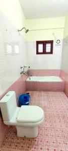 a pink bathroom with a toilet and a tub at Dew Drops Inn kovalam in Kovalam +8 photos