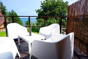 a balcony with white chairs and a table with a view at Engure BeachHouse in Engure