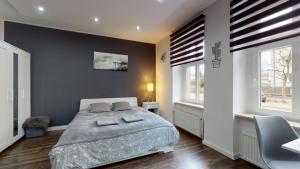 a bedroom with a large bed and two windows at Studio Fibra Dolce in Rybnik