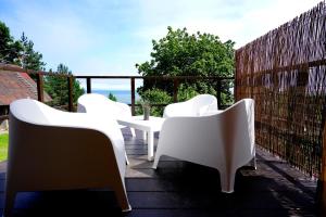 a group of white chairs and tables on a balcony at Engure BeachHouse in Engure