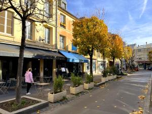 a woman walking down a street next to a building at Hôtel du Cheval Rouge in Versailles