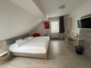 a bedroom with a bed and a table and a desk at Hotel & Restaurant Friedrichshöhe in Braunschweig
